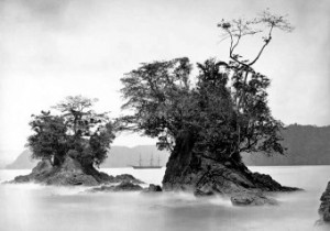 View of Three-Masted Sailing Ship Between Tree-Covered Rock Formations in Misty Harbor, 1870 sm  